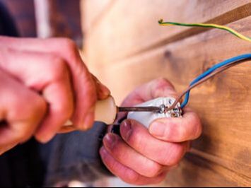 electrician's hand working on different coloured wires